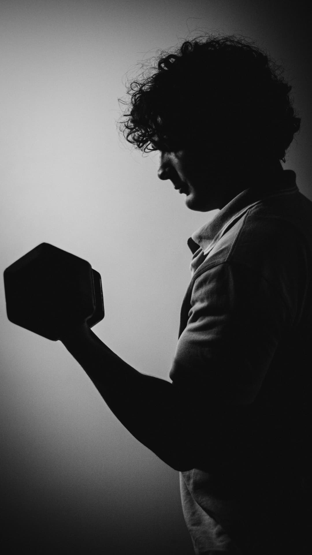 Joey DiCara holding a dumbbell in profile, black and white